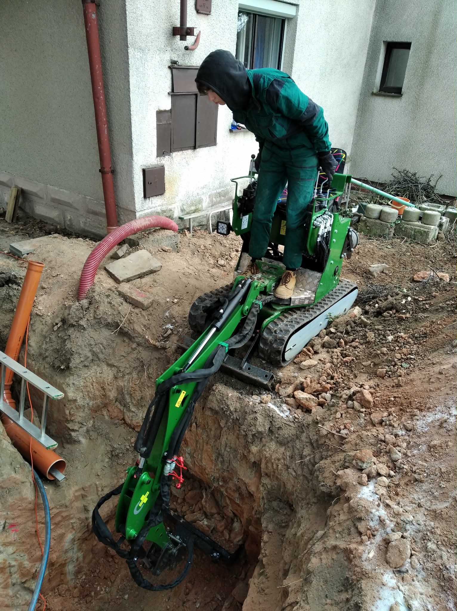 Kompaktní bagr v úzkém výkopu u domu